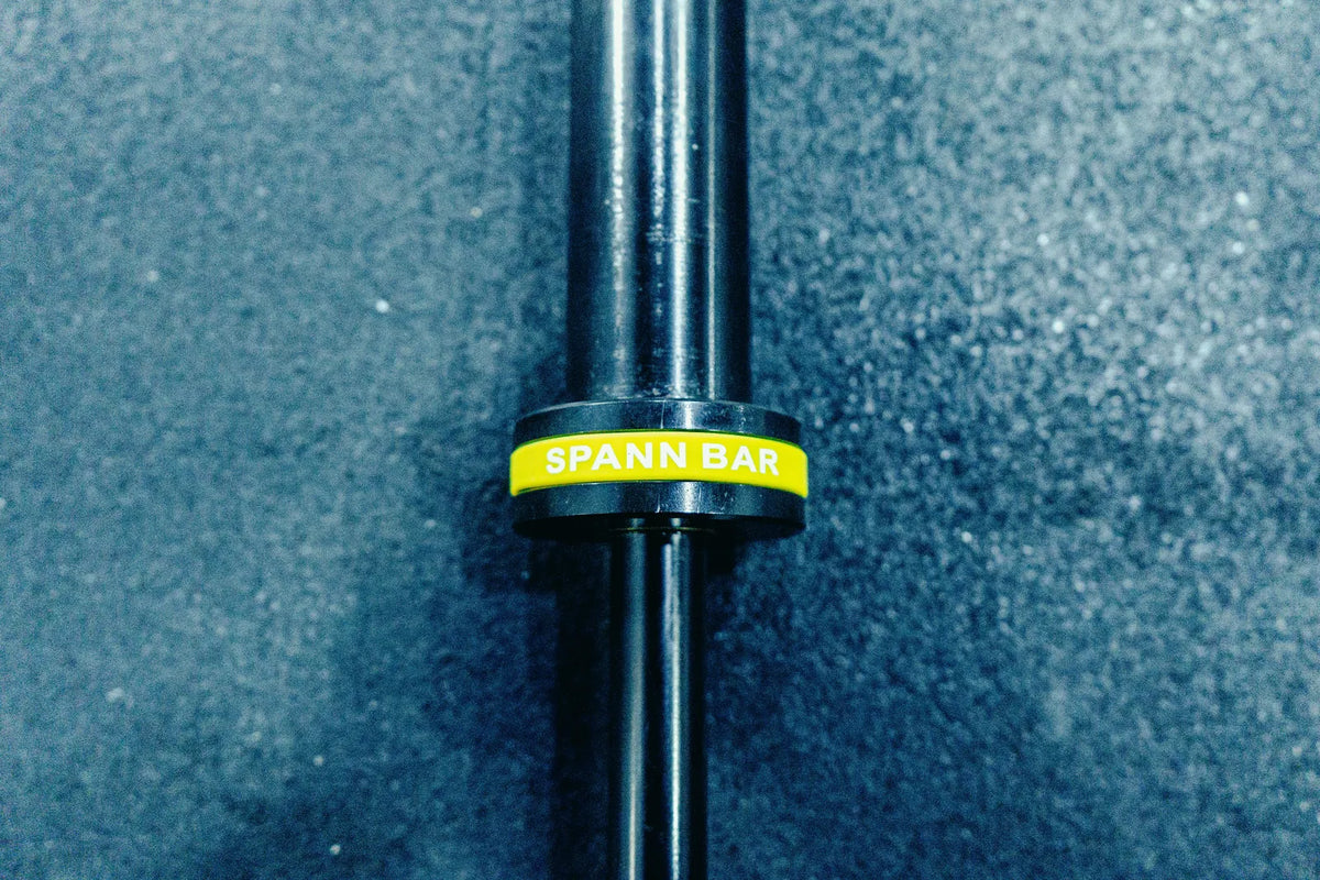 Melo Bar: Macro of the Melo Bar's yellow Spann Bar collar on a rubber gym floor.