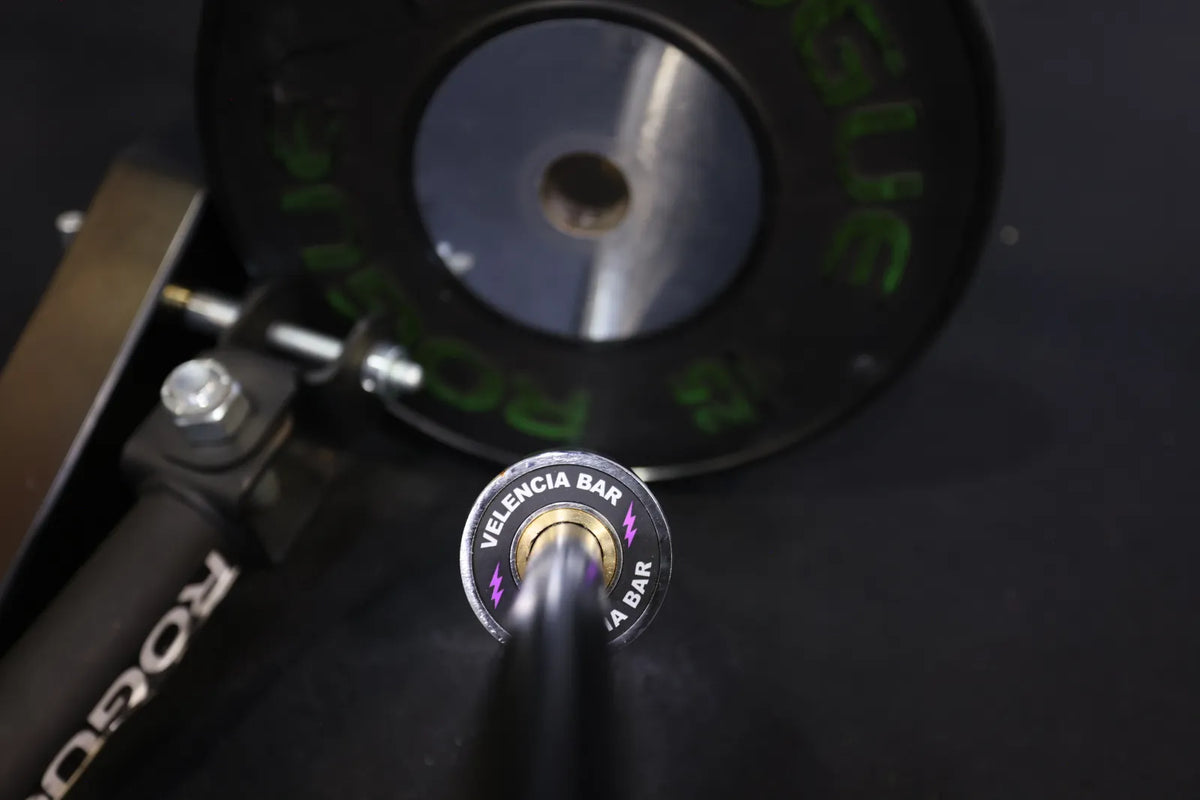 Velencia Bar: The Velencia Bar end cap, purple lightning bolts, in a landmine sleeve with a bumper plate behind it.